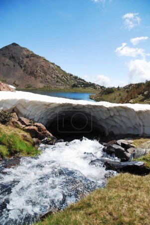 Photo for A vertical shot of a river flowing under an ice arch with a background of a lake between mountains - Royalty Free Image