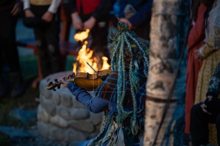 Photo for A closeup of a female playing violin next to the stone bonfire - Royalty Free Image