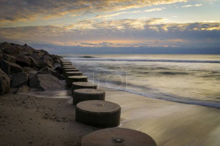 Photo for A long exposure of round wooden pilings on Folly Beach during sunset, Fort Fisher - Royalty Free Image