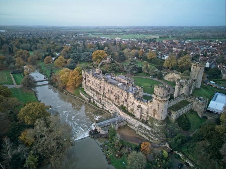An aerial shot of an old traditional Warwick Castle surrounded by trees and a river, Warwickshire, UK