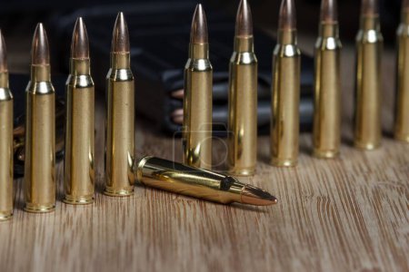 Photo for The 223 (5.56x45mm) bullets standing on end with one fallen, arranged by a loaded AR-15 clip - Royalty Free Image