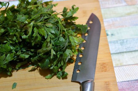 Photo for A vertical shot of celery leaves with a knife on the side on a wooden board - Royalty Free Image