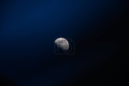 Téléchargez les photos : Une belle vue de la lune dans une phase gibbeuse croissante apparaissant dans le ciel bleu foncé - en image libre de droit