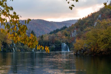 Foto de Un hermoso paisaje del bosque de otoño con una cascada que fluye a la orilla de un lago - Imagen libre de derechos