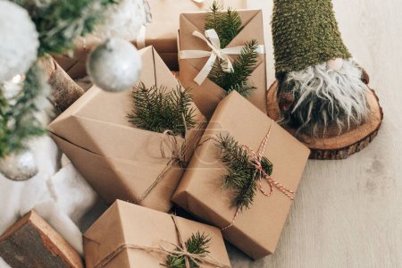 Foto de Regalos de Navidad envueltos en papel marrón y bajo el árbol de Navidad decorado - Imagen libre de derechos