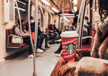 Téléchargez les photos : Un gros plan d'une femme tenant une tasse de café Starbucks sur le fond du métro - en image libre de droit