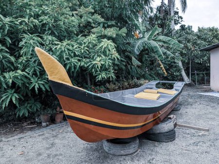 Photo for A vintage fishing boat raised on land to be repaired with trees in the background - Royalty Free Image