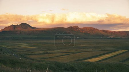 Téléchargez les photos : La vue sur les champs agricoles verts devant les montagnes sous un ciel nuageux couchant - en image libre de droit