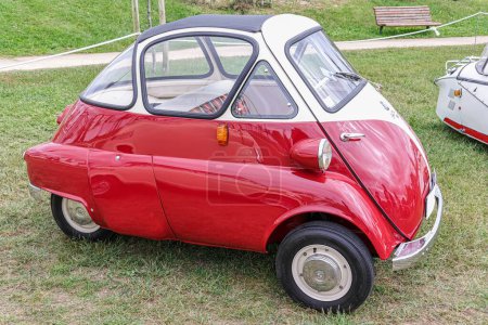 Photo for A side view of a beautiful classic three-wheel red BMW Isetta 300 in a field - Royalty Free Image