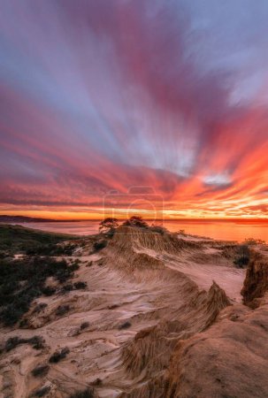 Foto de Una mágica vista de la costa frente al sol poniente iluminando el mar y el cielo - Imagen libre de derechos
