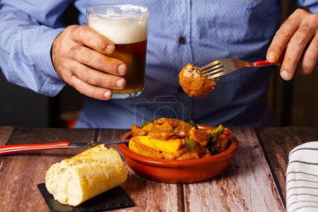 Photo for Man with  blue shirt eating meatballs with spaghetti in a restaurant with a glass of beer in his hand - Royalty Free Image
