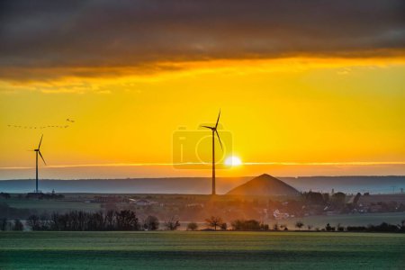 Téléchargez les photos : Lever du soleil avec vue sur les éoliennes et les tas miniers des mines de cuivre dans le sud des montagnes du Harz - en image libre de droit