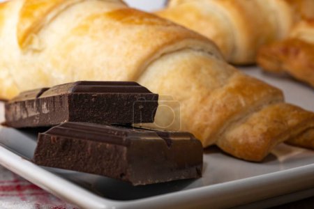 Téléchargez les photos : Une vue rapprochée de croissants sur une assiette avec des barres de chocolat noir - en image libre de droit