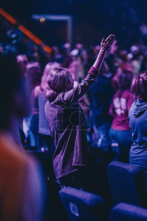 Téléchargez les photos : Un groupe de personnes dans le culte de l'église avec des effets de lumière bleue et violette - en image libre de droit