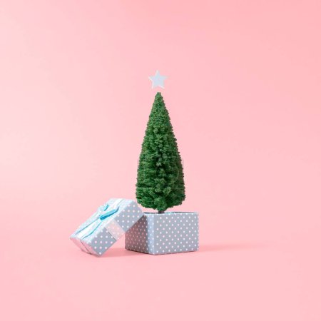 Foto de Un árbol de Navidad con una caja de regalo aislada sobre un fondo rosa. - Imagen libre de derechos