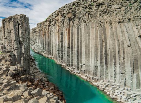 Téléchargez les photos : Le canyon de Studlagil avec des tons hexagonaux et un ruisseau d'eau verte pendant la journée - en image libre de droit