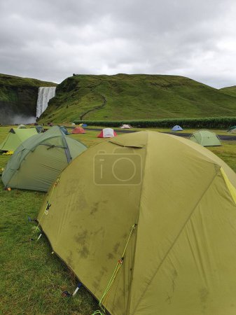 Téléchargez les photos : Un plan vertical de tentes vertes placées devant la cascade Seljalandsfoss en Islande - en image libre de droit