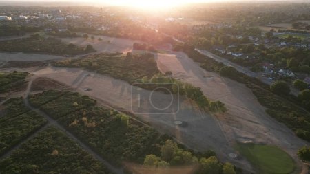 Foto de Una toma aérea de una puesta de sol sobre la ciudad y la tierra verde circundante. - Imagen libre de derechos