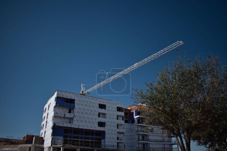 Foto de Vista de una grúa de construcción detrás del edificio sobre el fondo del cielo azul. - Imagen libre de derechos