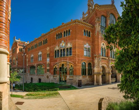 Photo for View Sant Pau Art Nouveau complex, work by architect Lluis Domenech i Montaner, details facade of a building with vegetation at front in a summer - Royalty Free Image