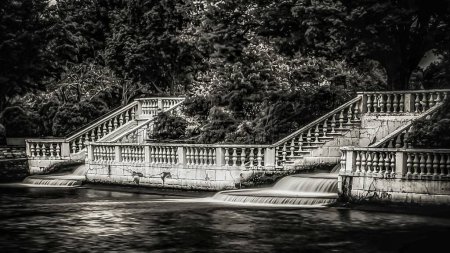 Photo for A grayscale of a beautiful garden with steps around a fountain flowing into a pond - Royalty Free Image