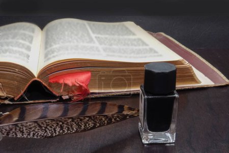 Foto de Un primer plano de tinta negra y una pluma cerca de un libro antiguo - Imagen libre de derechos