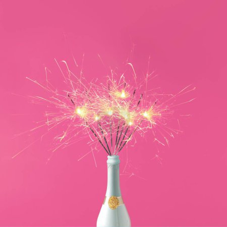 Photo for A bottle of champagne and sparklers on pink background - Royalty Free Image