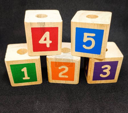 Téléchargez les photos : Blocs colorés avec des numéros un deux trois quatre et cinq, c'est un jouet pour les enfants d'apprendre à reconnaître les couleurs et les numéros, fond noir - en image libre de droit
