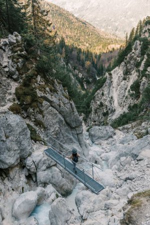 Foto de Mujer de pie en la pasarela sobre el torrente de montaña, mirando al paisaje en las cascadas de Gozd Martuljek en Eslovenia - Imagen libre de derechos