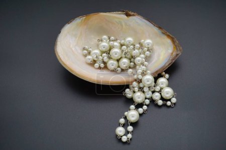 Foto de Un primer plano de un collar de perlas falsas extra largas en una concha de perlas - Imagen libre de derechos