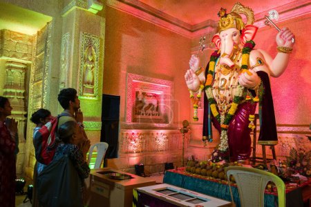 Téléchargez les photos : Personnes priant devant l'idole du Seigneur Ganesha, au festival Ganpati à Mumbai, en Inde - en image libre de droit