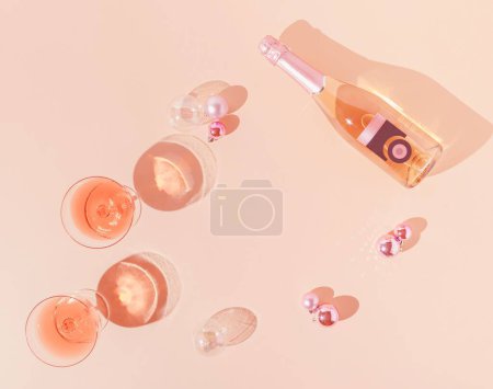 Photo for A top view of a pink champagne bottle and Christmas decoration against apricot color background-New Year party concept - Royalty Free Image