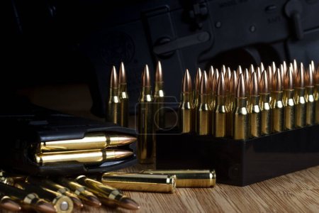 Foto de Las balas de 5.56x45mm en caja dispuestas libremente y en un cargador AR-15 completo en una placa de bambú - Imagen libre de derechos