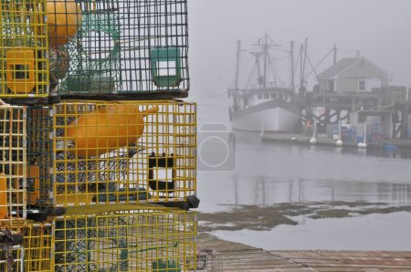 Foto de Niebla densa en el pueblo pesquero de Port Clyde en Maine. Colorido montón de trampas de langosta y tonos grises de arrastrero de pesca atracado en el puerto de niebla. - Imagen libre de derechos