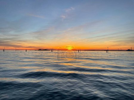 Téléchargez les photos : Une vue panoramique du coucher du soleil sur un paysage marin bleu avec des vagues soyeuses avec une lueur orange dans le ciel - en image libre de droit