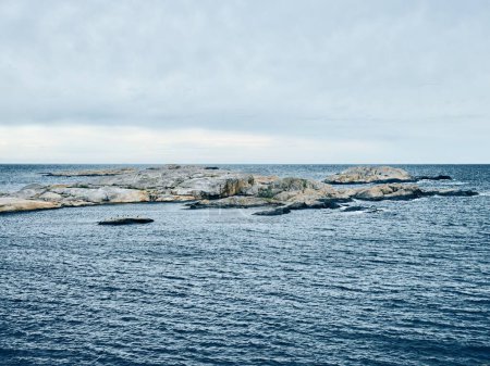 Téléchargez les photos : Vue des formations rocheuses au milieu de l'océan bleu, par temps nuageux - en image libre de droit