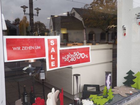 Photo for Red white sign with German words We are moving , sale, in store window, reflections, old building, lantern, decoration x-mas trees, angel, discount - Royalty Free Image