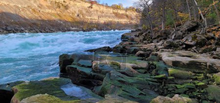 The Niagara River flowing by rocky cliff in Niagara Gorgeon a sunny day in Ontario Canada