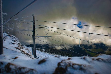 Foto de Un pintoresco plano de las líneas de un teleférico en una montaña nevada bajo el cielo nublado - Imagen libre de derechos