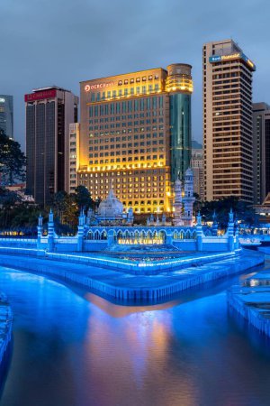 Photo for A vertical shot of Sultan Abdul Samad Jamek Mosque with water fountain lit in the evening in Kuala Lumpur, Malaysia - Royalty Free Image
