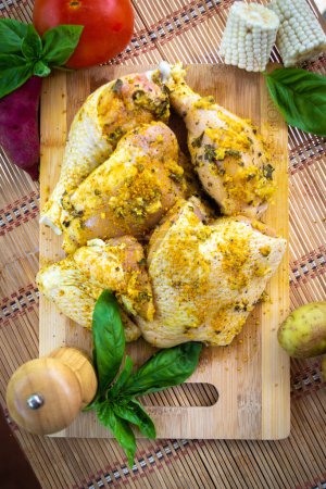 Photo for Several pieces of marinated chicken breast with turmeric and garlic, arranged on a wooden cutting board. Close-up shot with bokeh background - Royalty Free Image