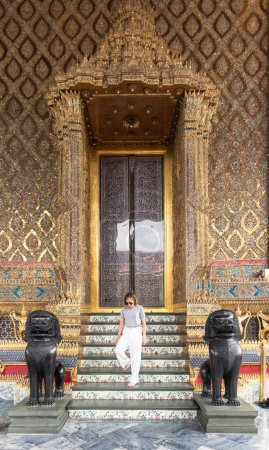 Photo for A Caucasian woman going down on the marble stairs of the Wat Phra Kaew Temple, Bangkok, Thailand - Royalty Free Image