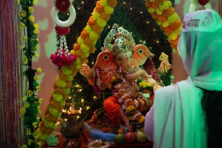 Foto de Una persona festejando en la colorida estatua de Ganesha en el templo - Imagen libre de derechos