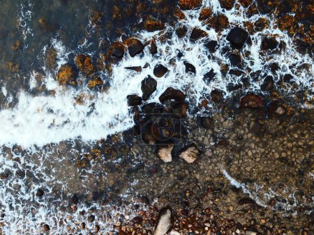 Téléchargez les photos : Une vue de dessus des vagues frappant le rivage rocheux - en image libre de droit
