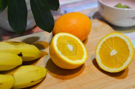 Foto de Un primer plano de una naranja en rodajas y otras frutas en una tabla de madera - Imagen libre de derechos