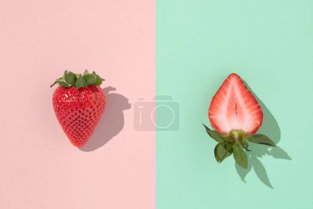 Photo for A whole and a sliced strawberry on a pink and blue background - Royalty Free Image