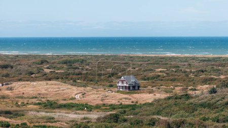 Photo for A lonely coastal house in wide grass field with beautiful view of the sea in the port town of Skagen, Denmark - Royalty Free Image
