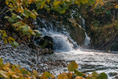 Foto de Una cascada rodeada de hojas amarillas en el Parque Nacional de los Lagos de Plitvice en Croacia - Imagen libre de derechos