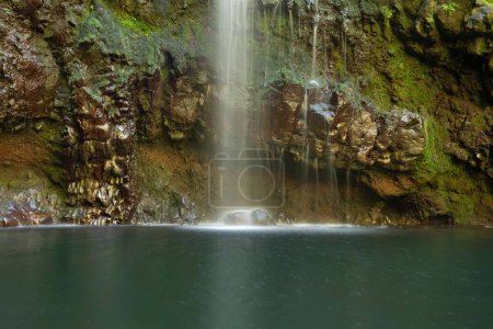 Téléchargez les photos : Un long plan d'exposition d'une cascade contre une falaise rocheuse avec de la mousse verte à Madère, Portugal - en image libre de droit
