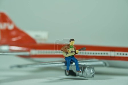 Téléchargez les photos : Un homme joue de la guitare sur une aile d'avion, humeur de vacances - en image libre de droit